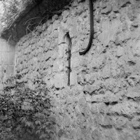 Vue partielle du mur nord de la nef unique romane, avec une fenêtre à linteau échancré, depuis le nord-ouest (1970)